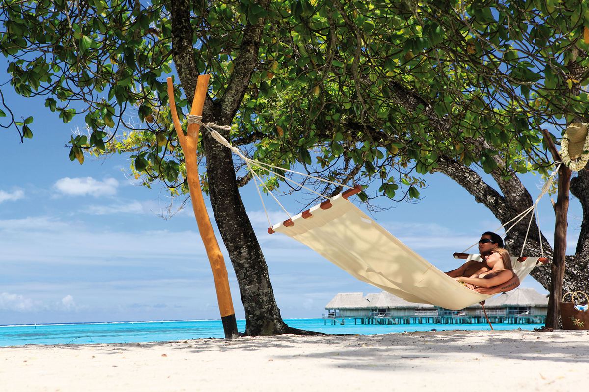 Un'amaca tesa fra due palme su una spiaggia di Moorea, davanti al mare.